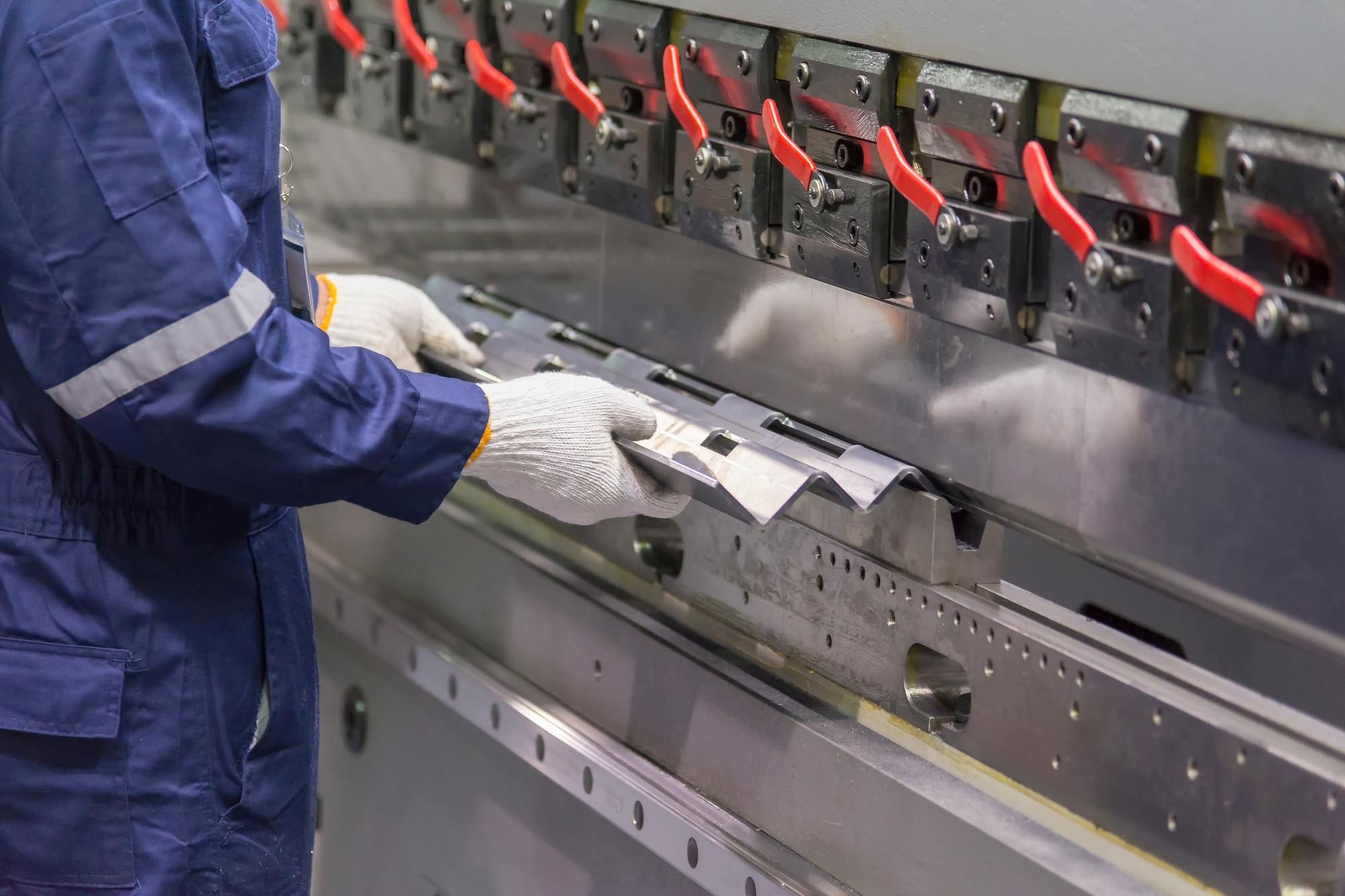 Operario técnico utilizando máquina hidráulica de doblado de chapa metálica